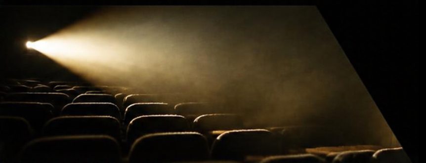 A projector beam shining over rows of empty cinema seats